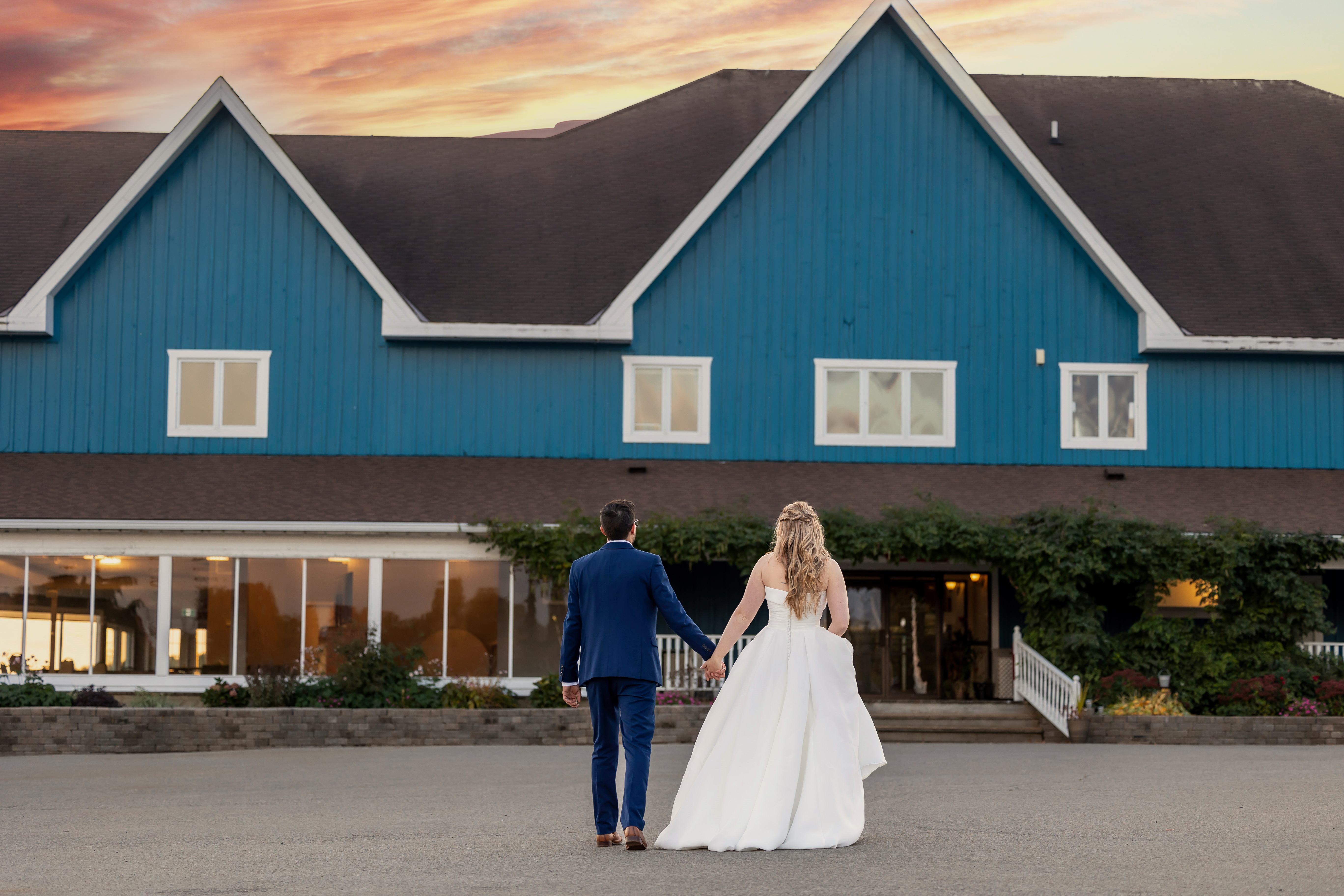 Bride and groom walking towards golf course clubhouse at sunset